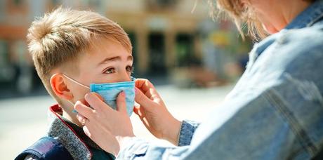 mother puts a safety mask on her son's face