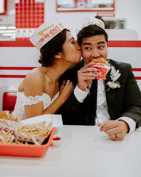 Bride and groom eating hamburger and fries