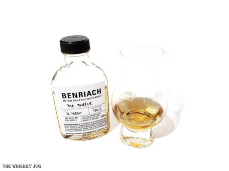 White background tasting shot with the BenRiach The Twelve bottle and a glass of whiskey next to it.