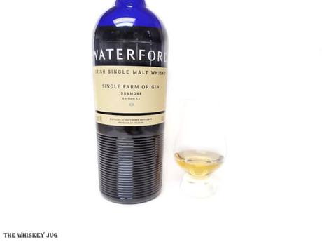 White background tasting shot with the Waterford Dunmore 1.1 bottle and a glass of whiskey next to it.