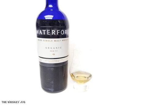 White background tasting shot with the Waterford Gaia 1.1 bottle and a glass of whiskey next to it.