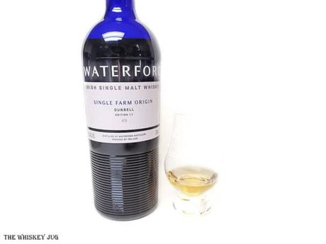 White background tasting shot with the Waterford Dunbell 1.1 bottle and a glass of whiskey next to it.