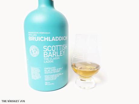 White background tasting shot with the Bruichladdich The Classic Laddie bottle and a glass of whiskey next to it.