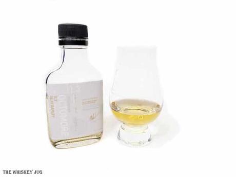 White background tasting shot with the Octomore 11.3 sample bottle and a glass of whiskey next to it.