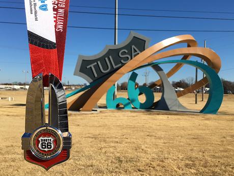 Route 66 medal in front of the Tulsa Route 66 Rising sculpture