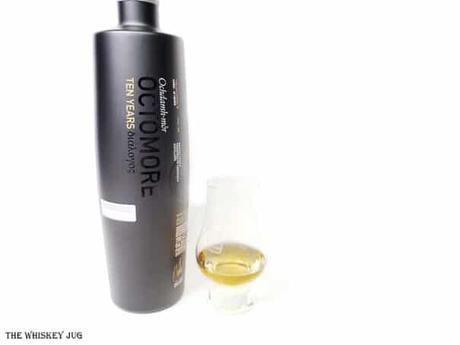 White background tasting shot with the Octomore 10 Years bottle and a glass of whiskey next to it.