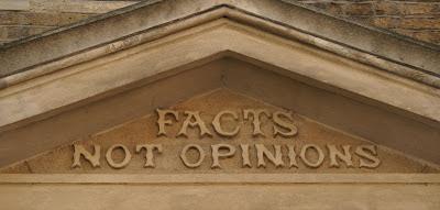 Photograph of a triangular stone pediment, inside which are the words 'Facts not opionions' in embellished Victorian lettering.