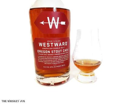 White background tasting shot with the Westward Oregon Stout Cask Single Malt Whiskey bottle and a glass of whiskey next to it.