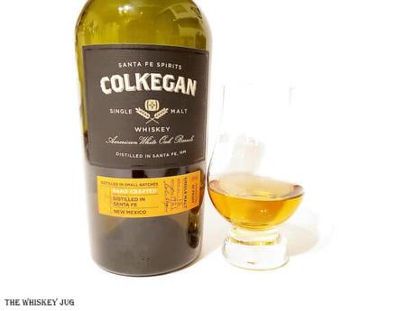 White background tasting shot with the Colkegan Santa Fe Single Malt bottle and a glass of whiskey next to it.