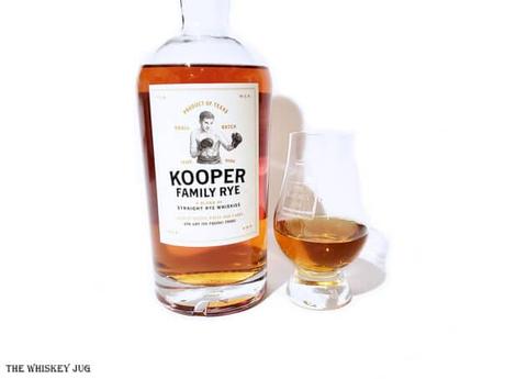 White background tasting shot with the Kooper Family Rye bottle and a glass of whiskey next to it.