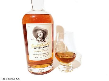 White background tasting shot with the Sweetheart of the Rodeo Bourbon bottle and a glass of whiskey next to it.