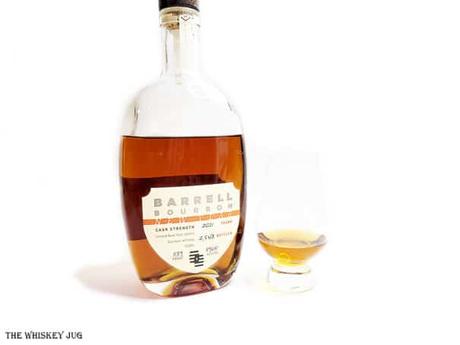 White background tasting shot with the Barrell Bourbon New Year 2021 bottle and a glass of whiskey next to it.