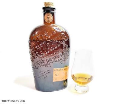White background tasting shot with the Bib and Tucker Bourbon 10 Years bottle and a glass of whiskey next to it.