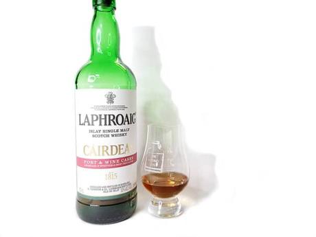 White background tasting shot with the Laphroaig Cairdeas 2020 bottle and a glass of whiskey next to it.