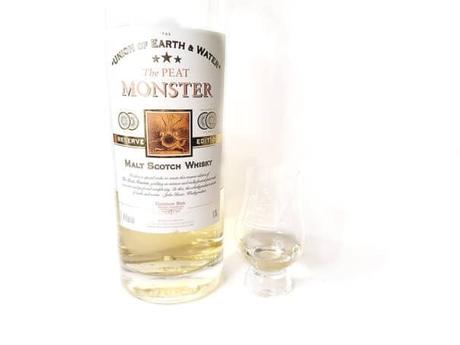 White background tasting shot with the Peat Monster Reserve Edition bottle and a glass of whiskey next to it.