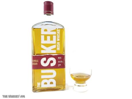 White background tasting shot with the Busker Single Grain Irish Whiskey bottle and a glass of whiskey next to it.