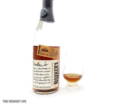 White background tasting shot with the Booker's 2020-03 Pigskin Batch bottle and a glass of whiskey next to it.