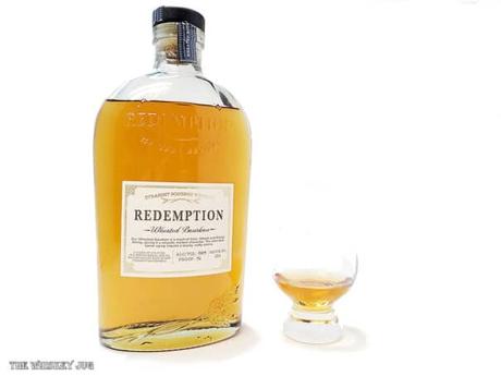 White background tasting shot with the Redemption Wheated Bourbon bottle and a glass of whiskey next to it.