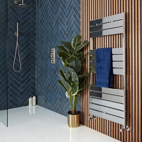 chrome heated towel rail on a wooden bathroom wall