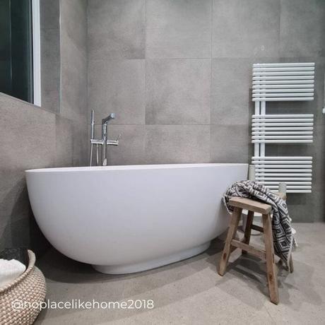 white ladder style heated towel rail in a gray bathroom