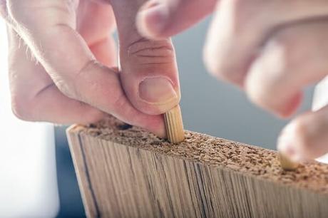 Man assembling furniture at home, hand with wooden dowel pins