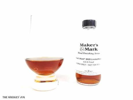 White background tasting shot with the Maker's Mark 2020 Wood Finishing Series bottle and a glass of whiskey next to it.