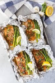 Salmon does well being wrapped in foil while it is cooking as it retains the flavors of the aromatics used during the cooking process. Four Salmon Fillets On A Baking Tray In Foil With Asparagus And Lemon Wedges With Garlic And Lemon I Salmon Fillet Recipes Spring Recipes Dinner Cooking Salmon