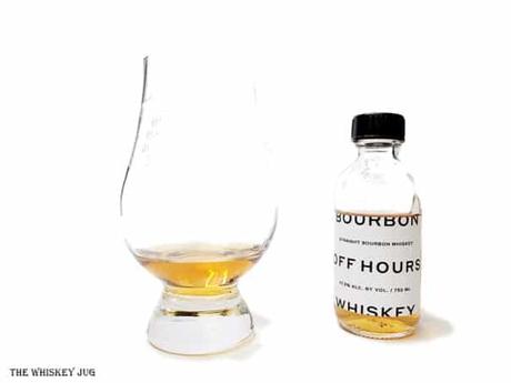 White background tasting shot with the Off Hours Bourbon Whiskey bottle and a glass of whiskey next to it.