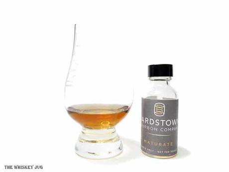 White background tasting shot with the Bardstown Bourbon Company Maturate bottle and a glass of whiskey next to it.