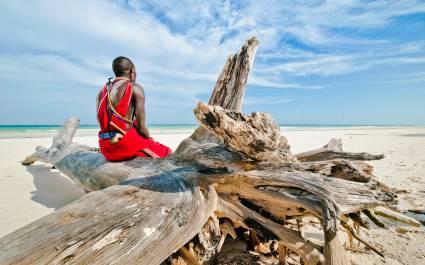 Man from the Maasai tribe sits on the shore of the Indian ocean