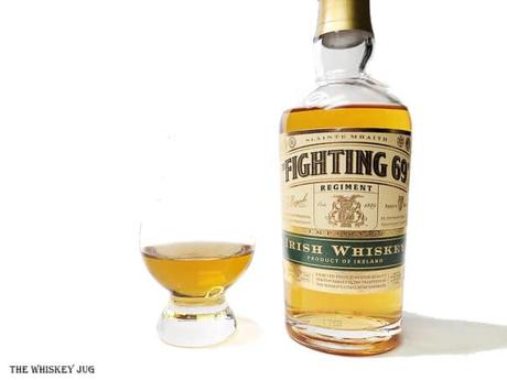 White background tasting shot with the Fighting 69th Irish Whiskey bottle and a glass of whiskey next to it.