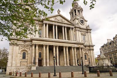 Photograph of the west facade of St Paul's Cathedral, taken from the north-west. The steps leading up to the cathedral doors are empty. In the foreground to the right is the statue of Queen Anne.