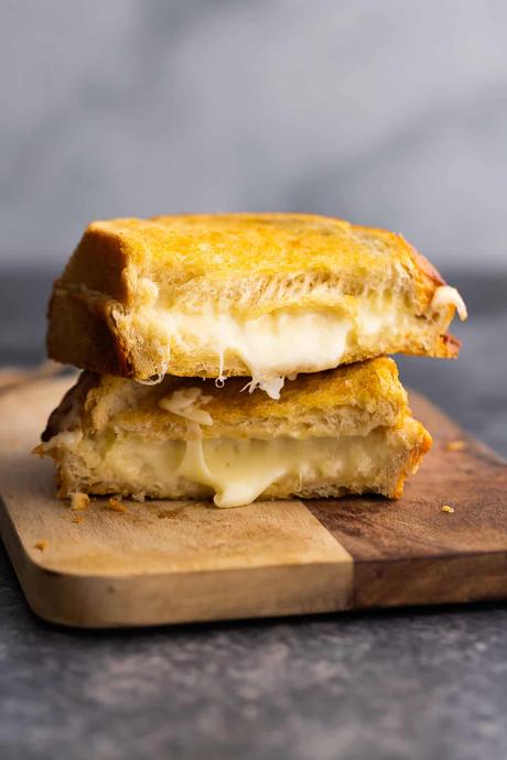 grilled cheese stacked on cutting board revealing melted cheese