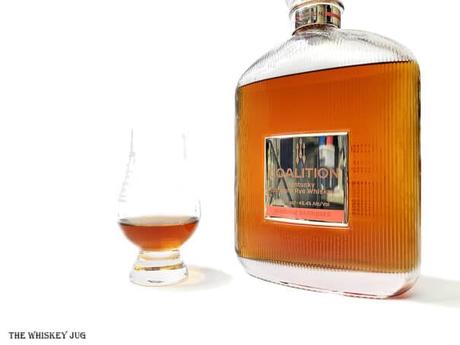 White background tasting shot with the Coalition Rye Margaux Barriques bottle and a glass of whiskey next to it.