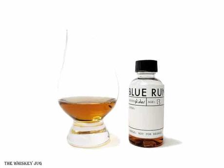 White background tasting shot with a Blue Run Bourbon Whiskey (winter) sample bottle and a glass of whiskey next to it.