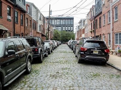 Cobblestone streets, overhead wires, and a sticker [Hoboken]
