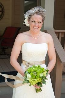 bride in strapless dress with tan sash and green bouquet