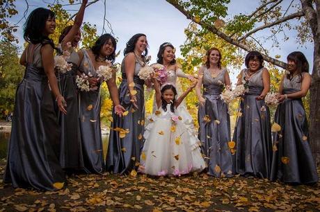 bridesmaids in gray silk dresses play in leaves with flower girl