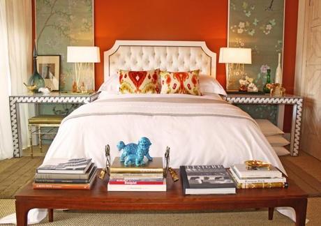 rich orange bedroom, white bedspread, ikat pillows, tufted white headboard, decorative panels as artwork