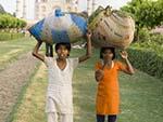 Two local Indian girls carrying bags of grass clippings on their heads