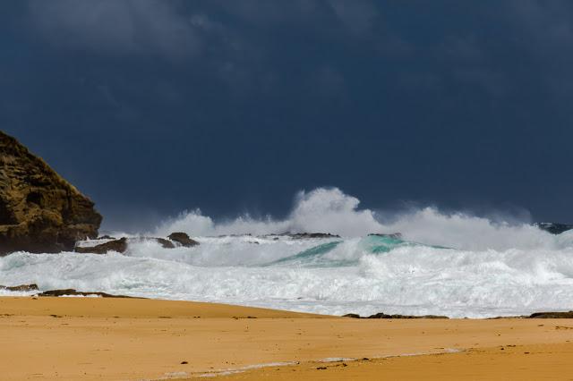 waves breaking on beach with dark sky behind