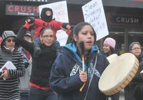  - Tamara Napoleon of Lillooet beats a drum while marching with others along Victoria Street Friday. Behind her, Lacey Tallio carries 15-month-old Cruz Seymour on her shoulders. - Murray Mitchell