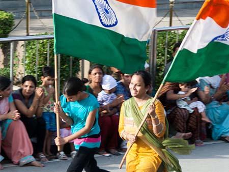 Two girls running with a large Indian flag