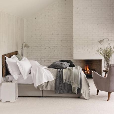 neutral texture bedroom white brick fireplace gray wood bed