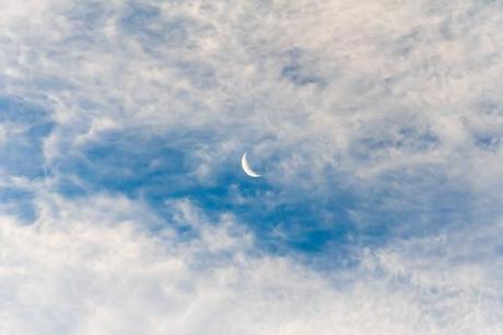 crescent moon behind evening clouds