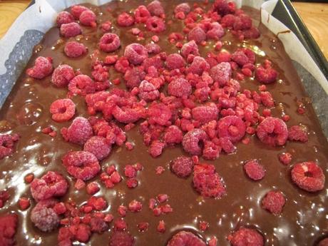 Uncooked brownie mixture in a tray with raspberries on top