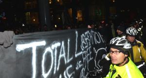 Cop screened by black bloc banner.