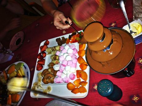 Chocolate fondue fountain on a table with fruit and sweets