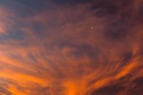 moon behind red clouds at sunset
