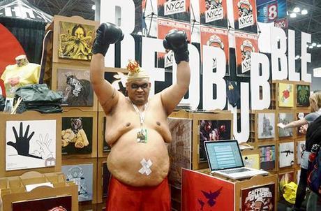 fat guy wearing some kind of boxer superhero costume and posing in front of RedBubble booth at 2012 New York Comic Con comics and pop culture convention